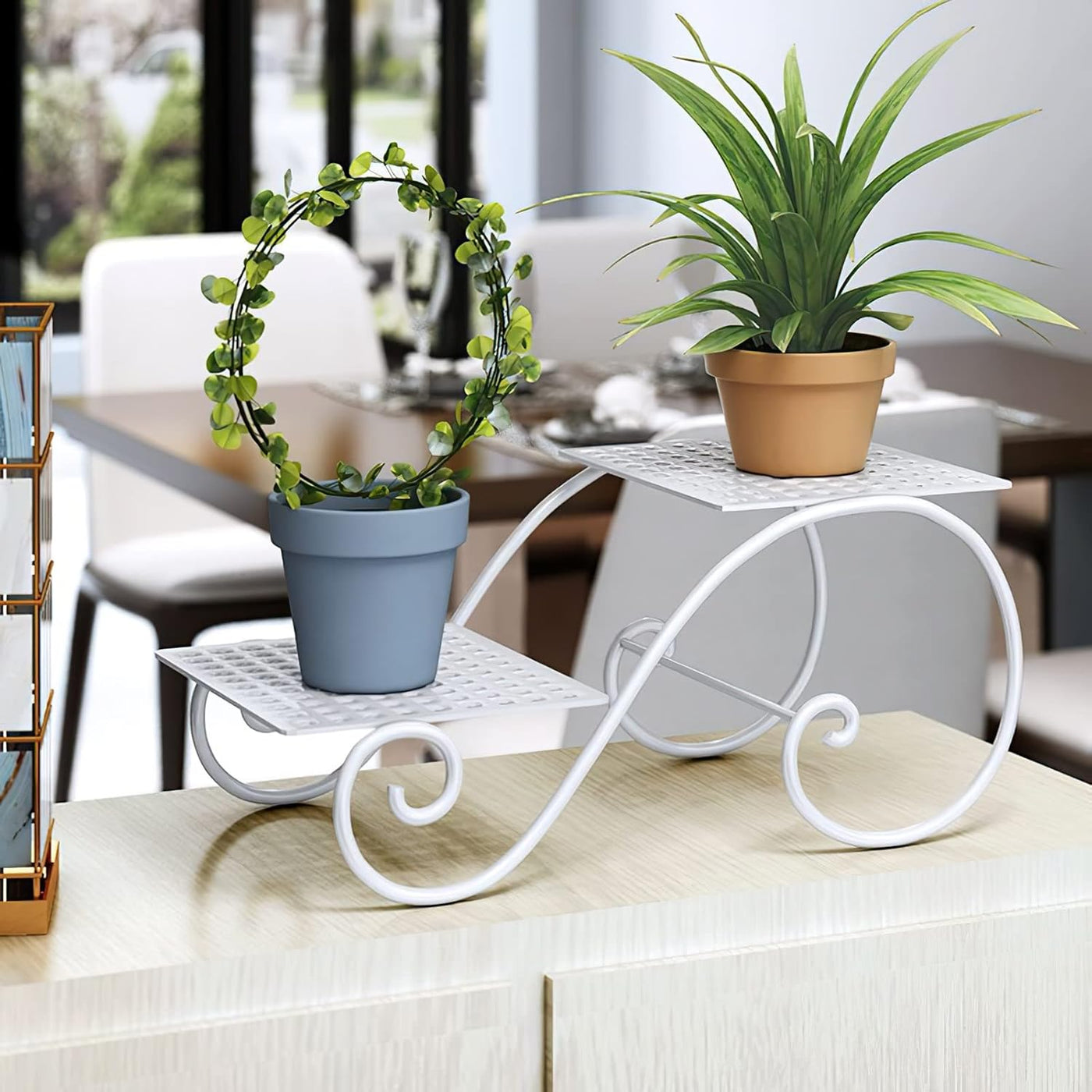 White wrought-iron two-tier plant stand with curved scroll legs, displaying two potted plants on a kitchen counter.