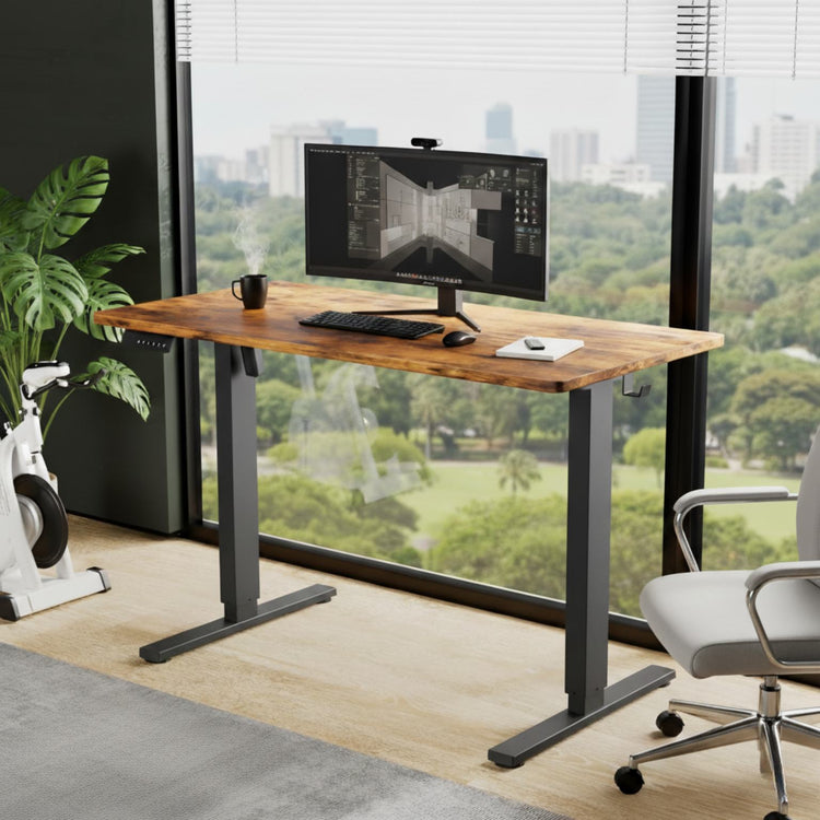 Wooden desk with computer setup in a modern office with large windows.