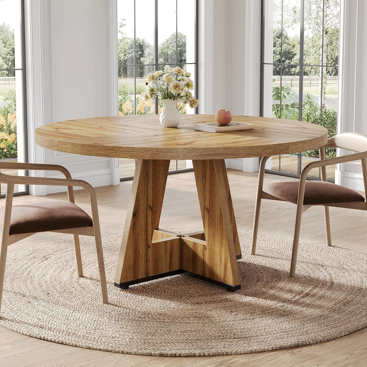 Wooden dining table with chairs in a bright room with large windows.