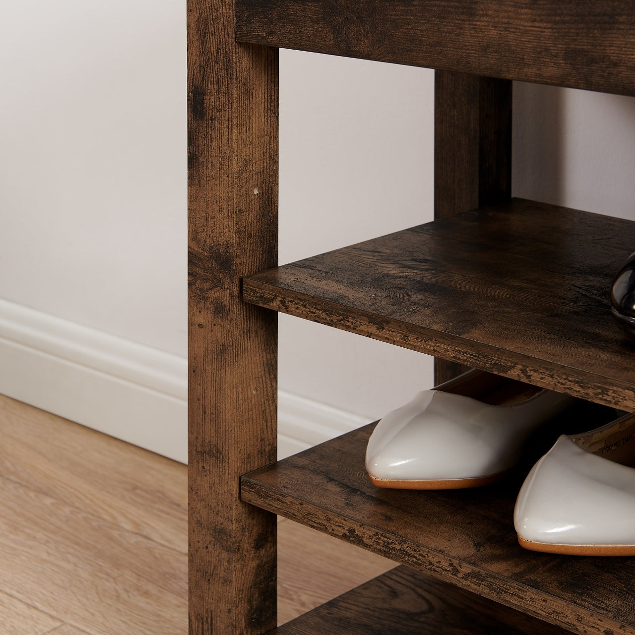 Wooden shoe rack with white shoes on a light wooden floor.