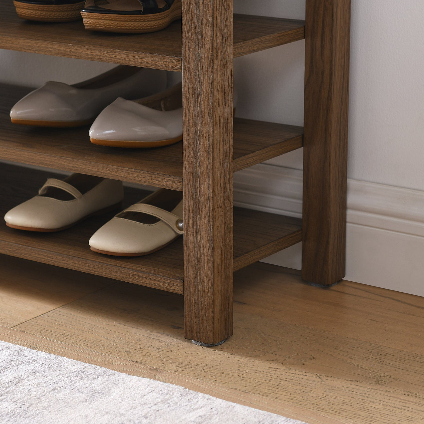 Wooden shoe rack with white shoes on a wooden floor.