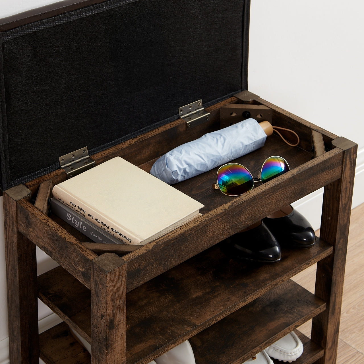 Wooden shoe storage bench with items on top including books, an umbrella, and sunglasses.