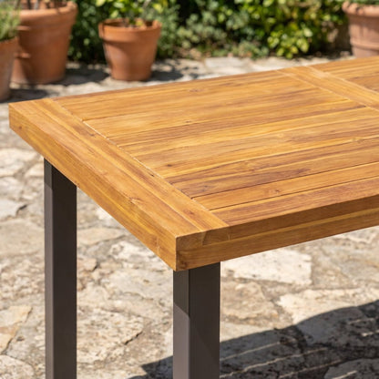 Framed acacia plank top and breadboard edge at the corner of the six-seat indoor-outdoor dining table (close-up detail)