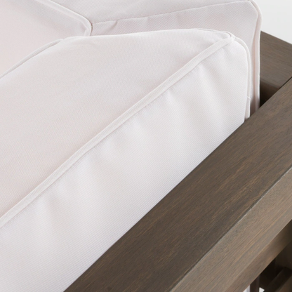 Piped seam on the water-resistant cushion cover where it meets the acacia arm rail, close-up detail