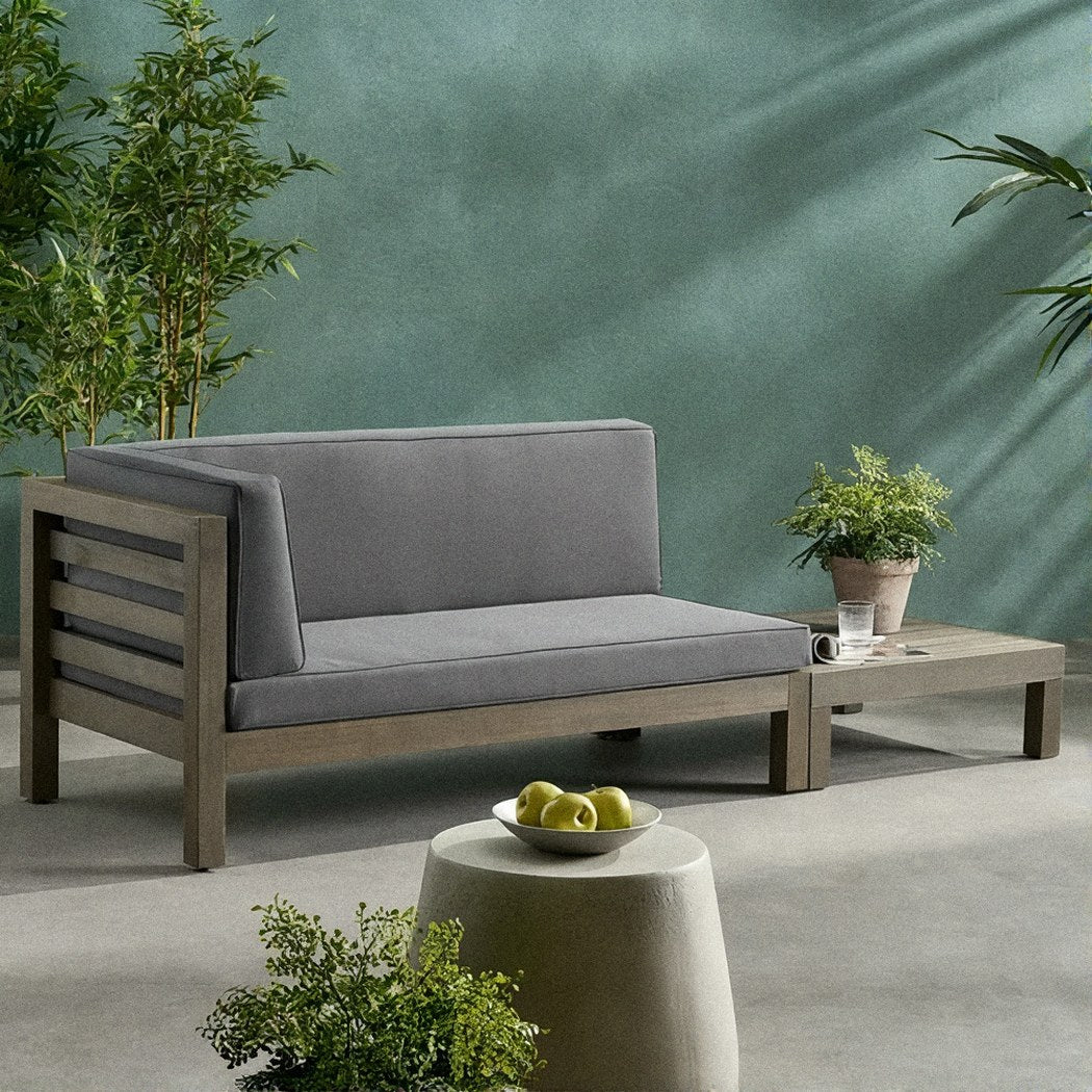 Acacia loveseat with dark grey cushions and its slatted coffee table on the same garden patio terrace