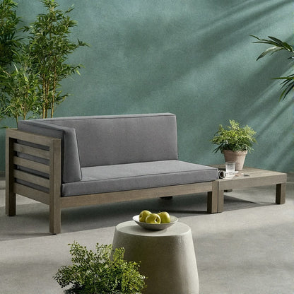 Acacia loveseat with dark grey cushions and its slatted coffee table on the same garden patio terrace