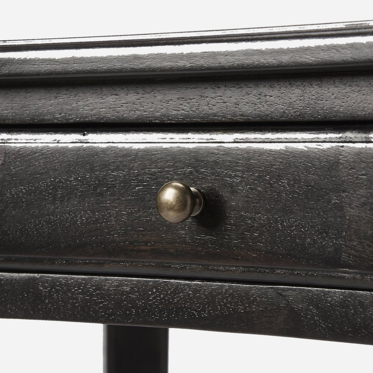 Drawer front with a small round knob on a black desk (close-up detail)