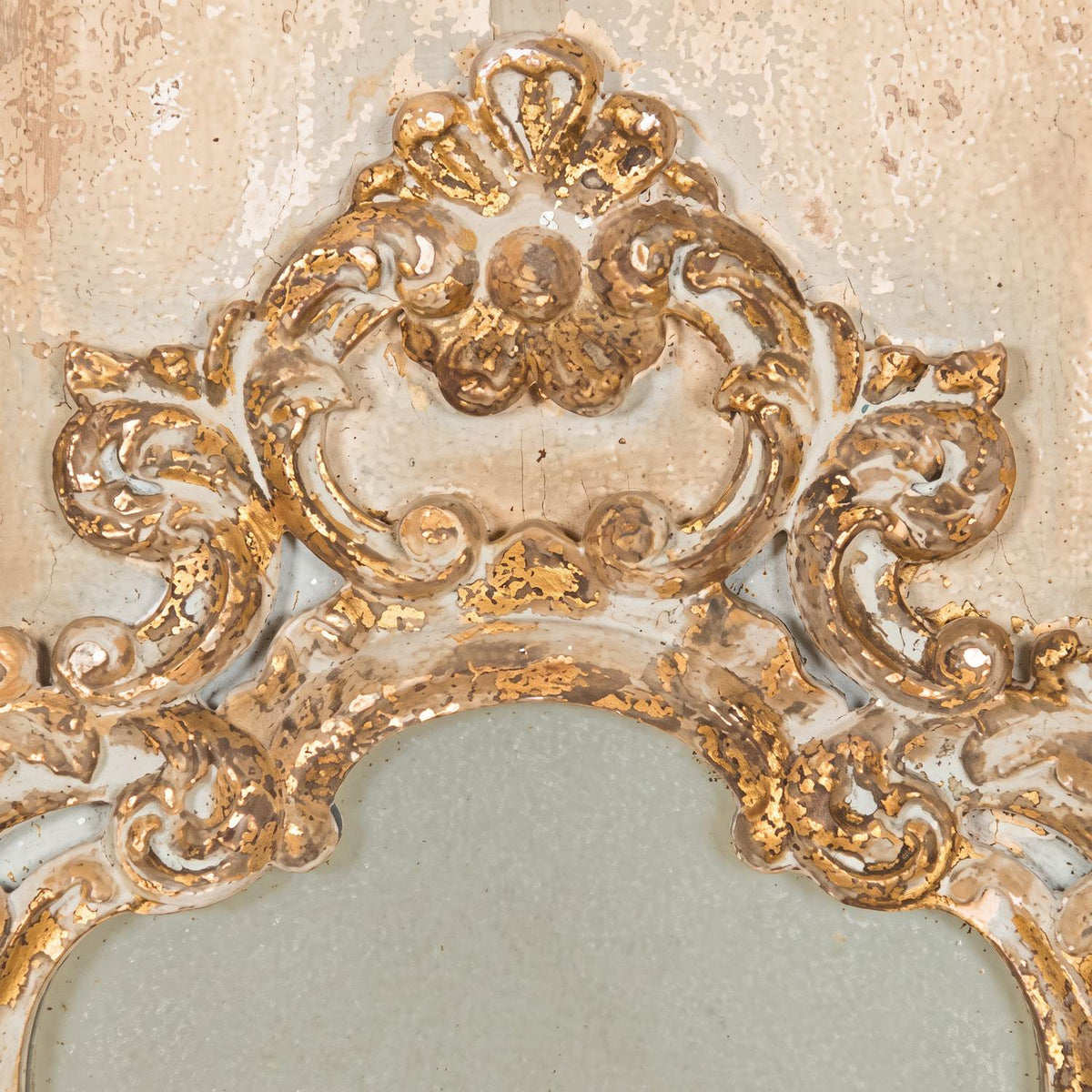 Close-up of the carved shell crest with worn gold leaf over cream paint