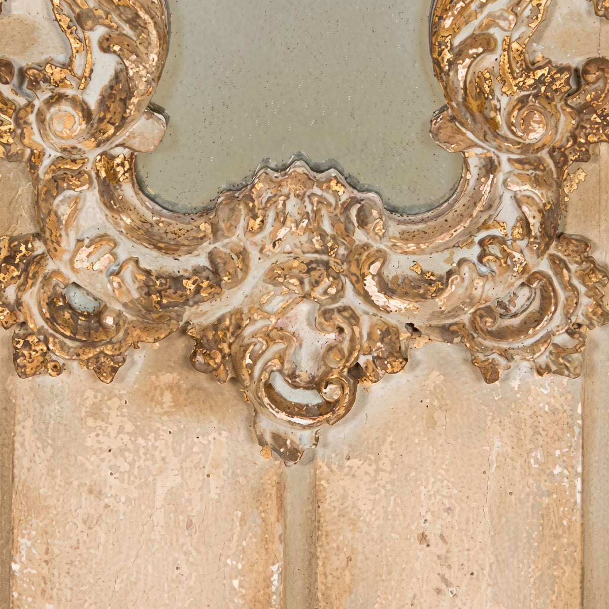 Close-up of the carved cartouche and mask below the mirror glass, gilt wear on cream