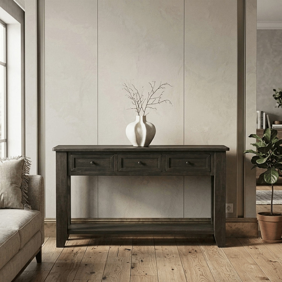 The table beside a linen sofa on oak floors, a white vase of branches on top