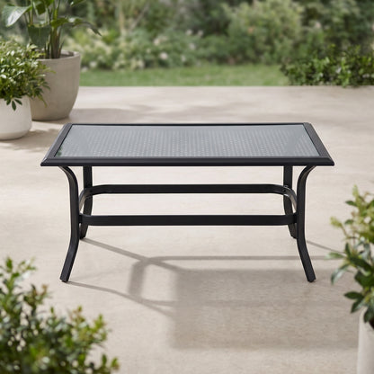 Black metal outdoor coffee table on a patio with greenery in the background