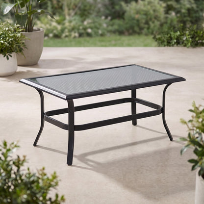 Black metal outdoor coffee table on a patio, angled view with greenery