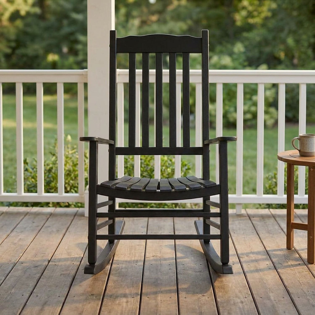 Black porch rocking chair seen from the front on a wooden porch beside a side table