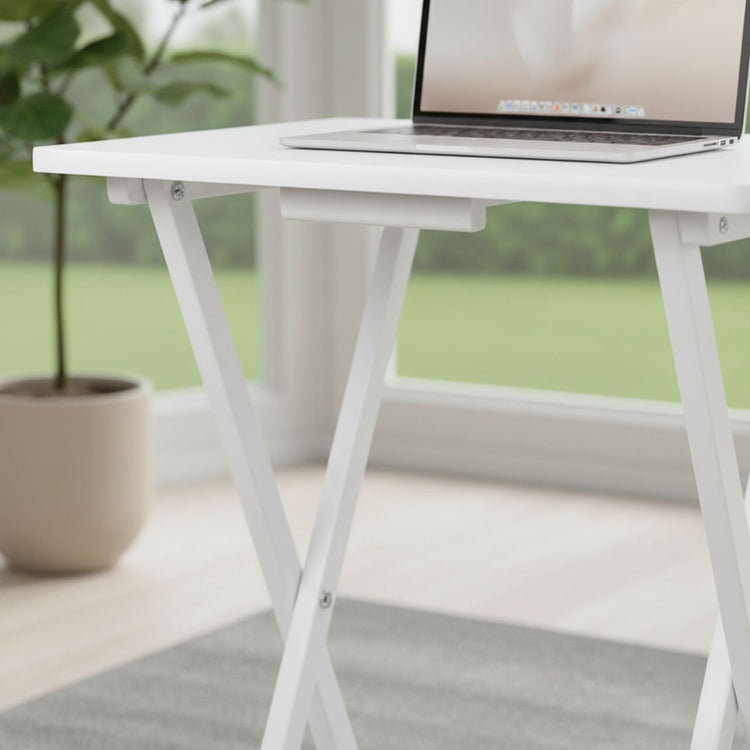 White folding table with a laptop on it, placed indoors with a blurred green outdoor background.
