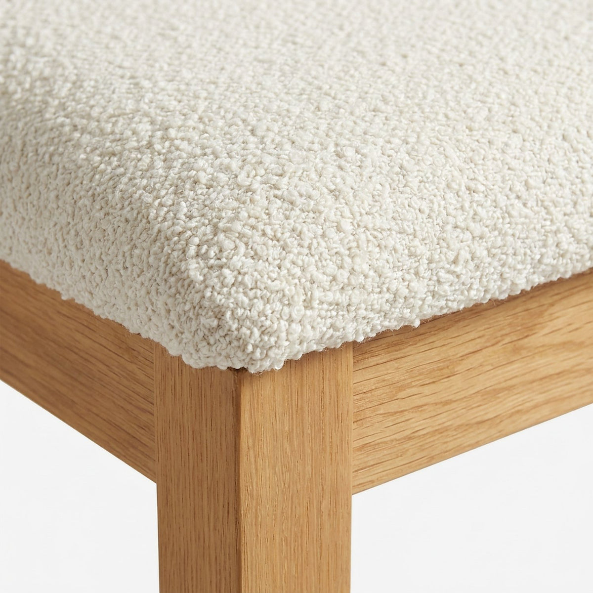 Close-up of the looped cream boucle seat corner over the wood apron