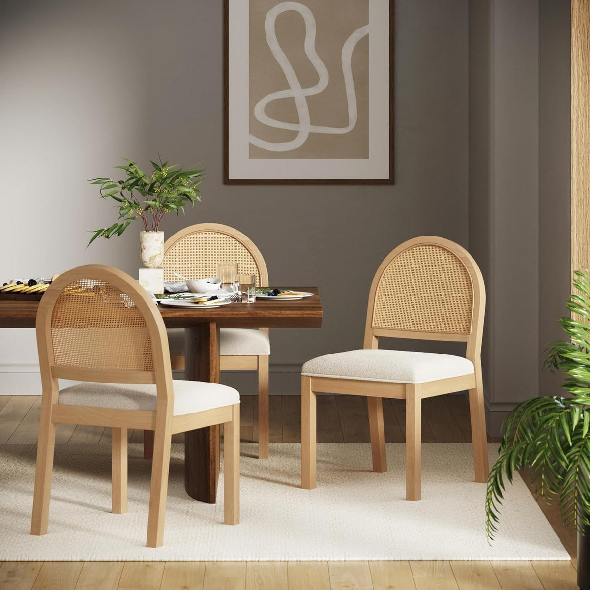 Three cane back boucle chairs around a walnut dining table, wider room view