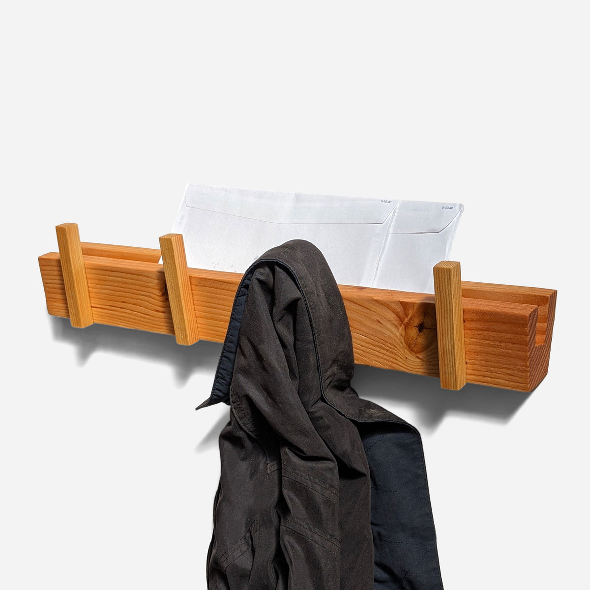 Decorative wall coat rack in reclaimed fir with a camel coat and mail in the top slot, straight front view