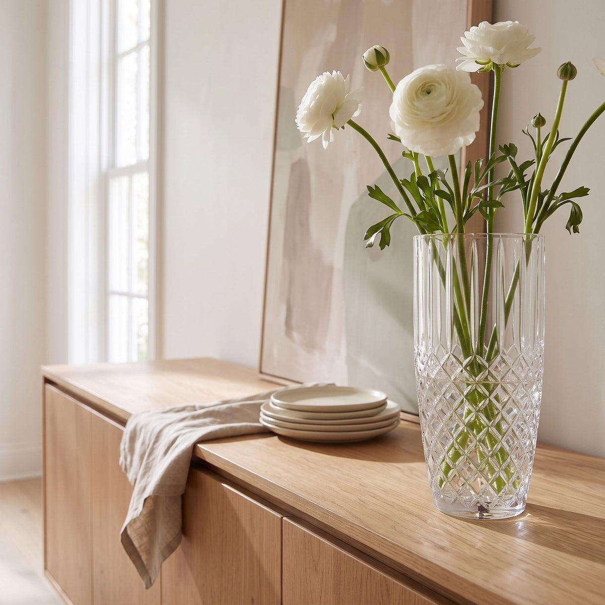 Cut crystal vase with white flowers close up on the same sideboard, window light glinting through the cuts