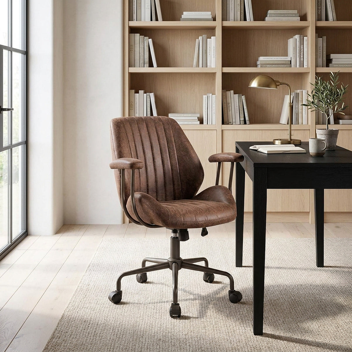 Desk chair pulled in at a black oak desk in a bright home library study