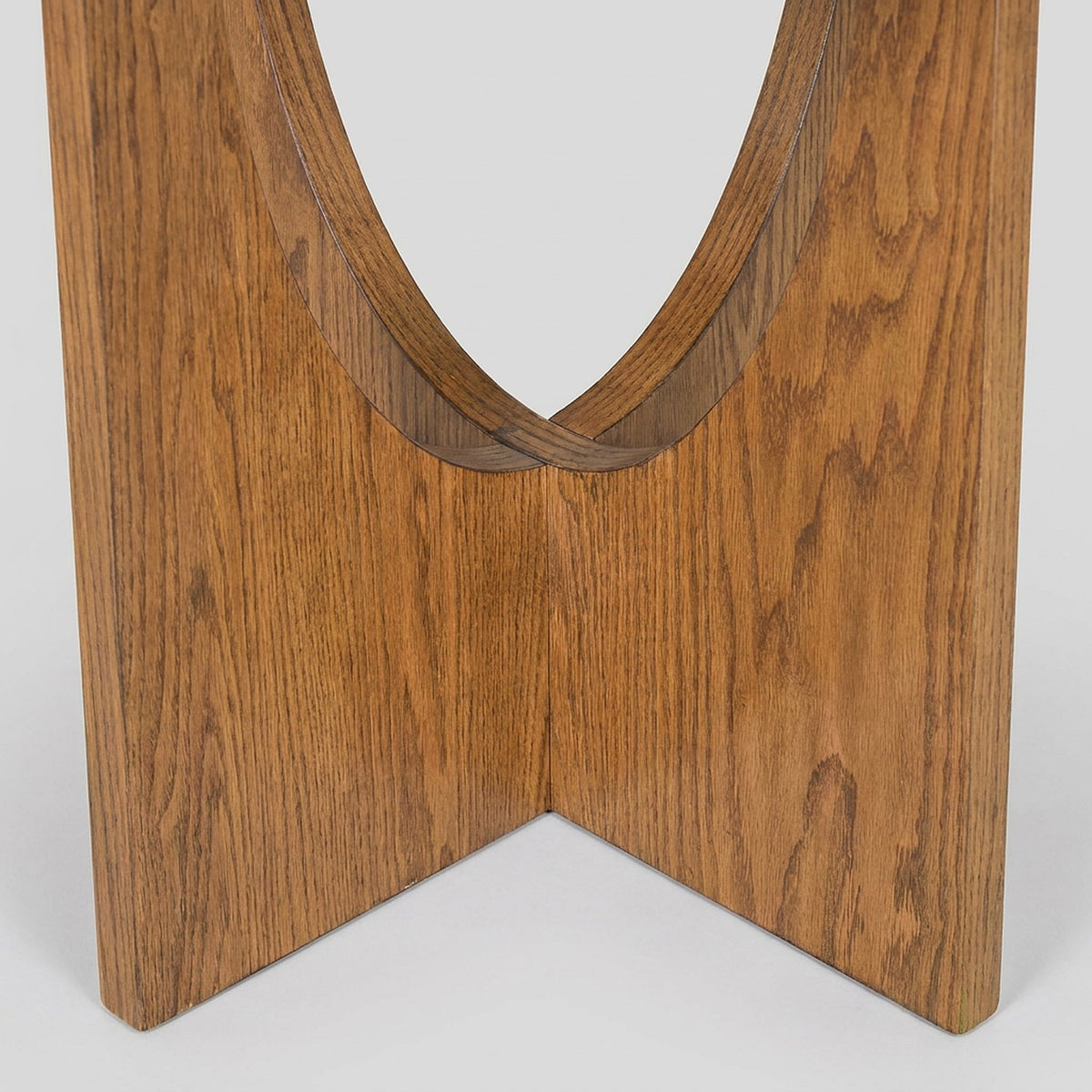 Close-up of the pedestal base with crossed legs and an arched cut-out in walnut tone