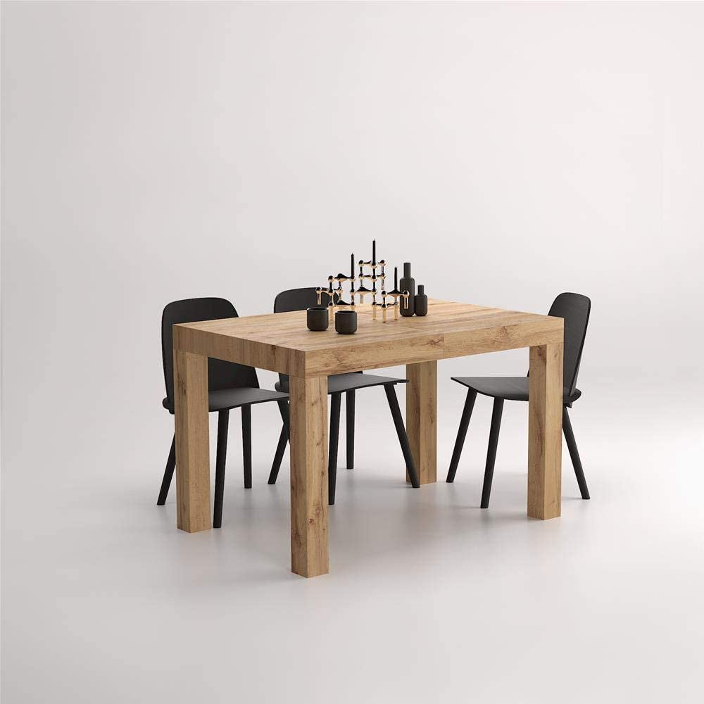 The oak table styled with six black dining chairs and a dark sculptural centrepiece
