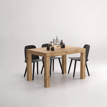 The oak table styled with six black dining chairs and a dark sculptural centrepiece
