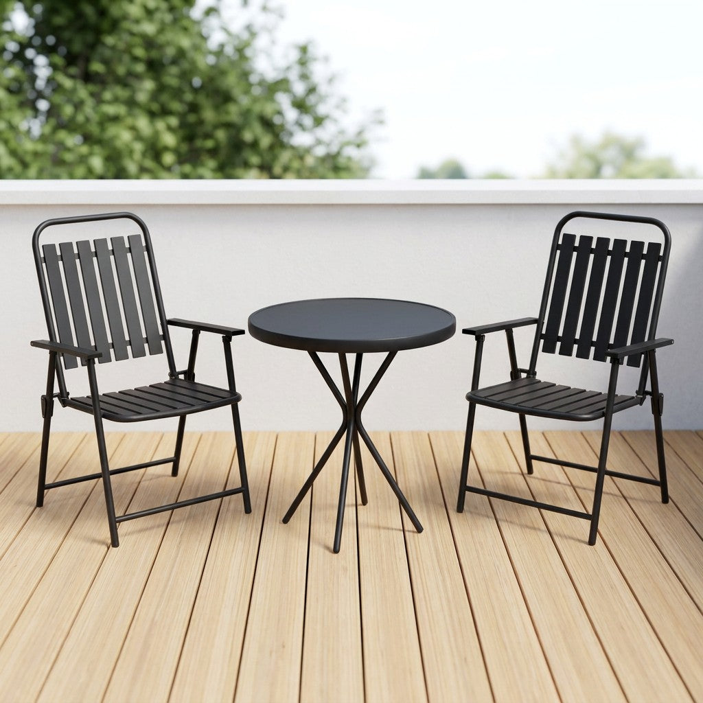 Black bistro table and two folding chairs on a wood-deck balcony terrace beside a white parapet wall