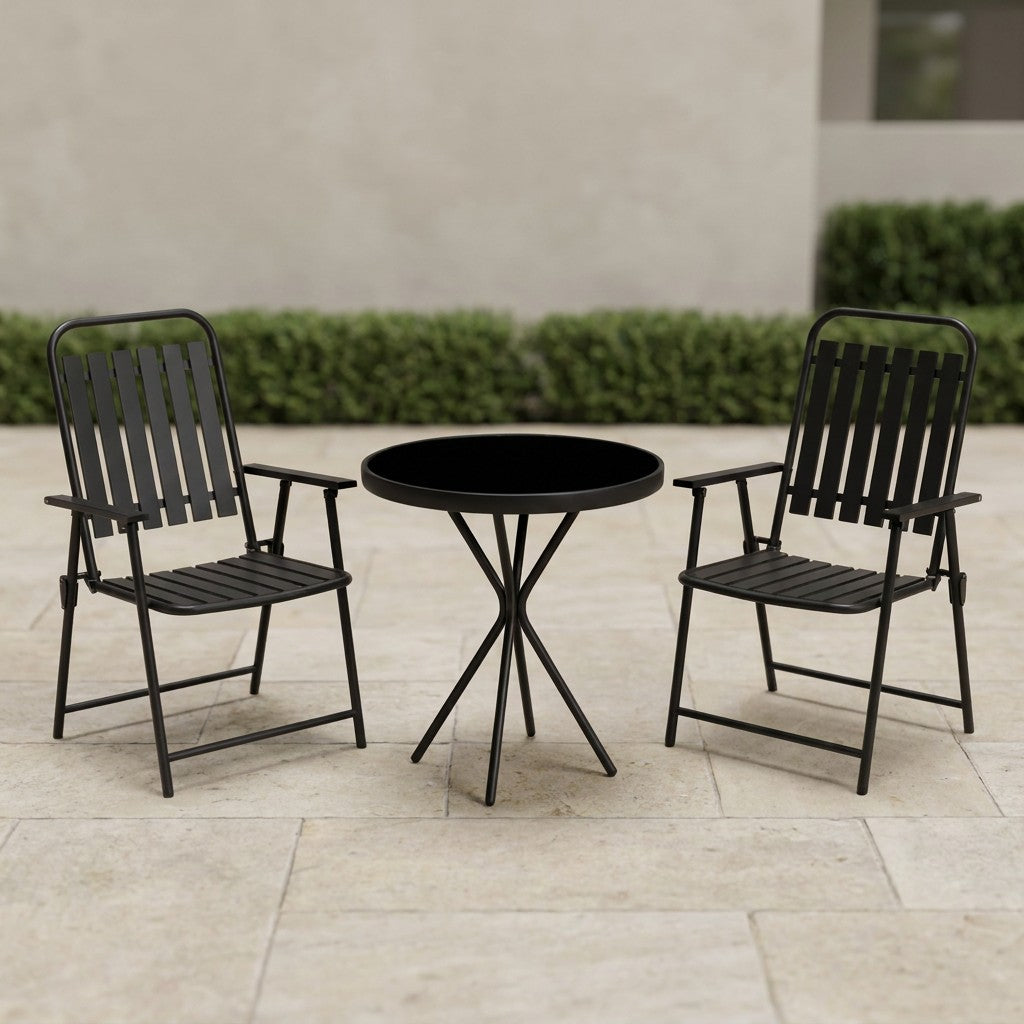 Black bistro set on a stone patio terrace with a clipped hedge behind
