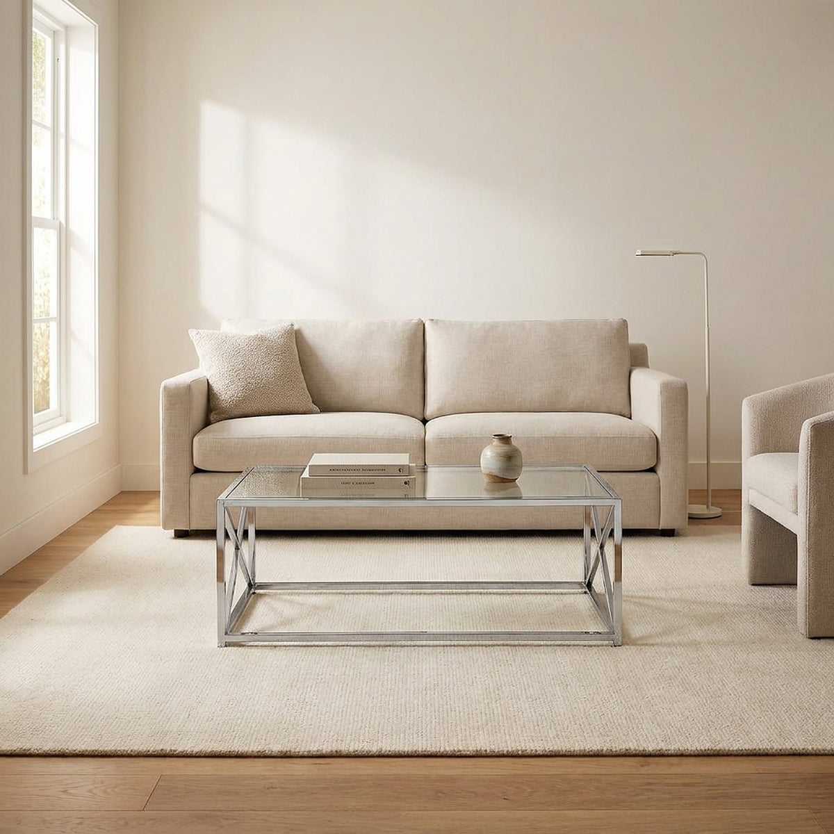 Chrome-framed glass table centered before a cream sofa in a sunlit living room