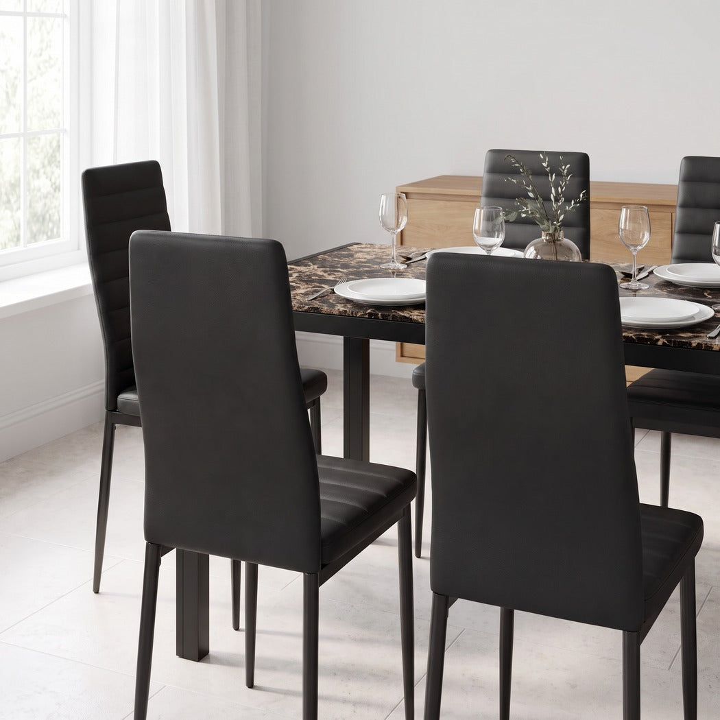 Marble-print glass dining table with tucked-in black chairs in a modern dining room