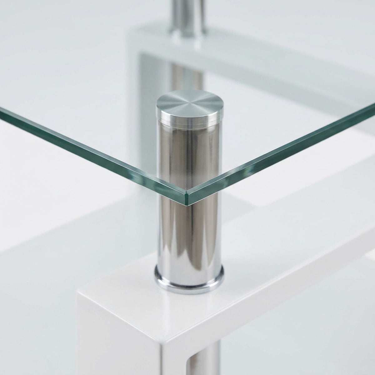Close-up of a clear tempered glass tabletop corner resting on a chrome post above a white frame