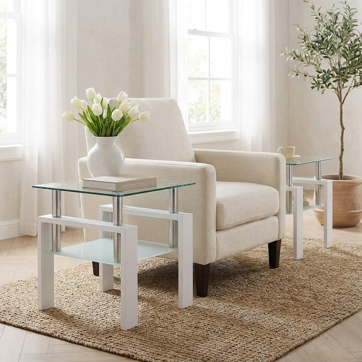 White-frame glass end table with tulips and books beside a cream armchair in a bright sitting room
