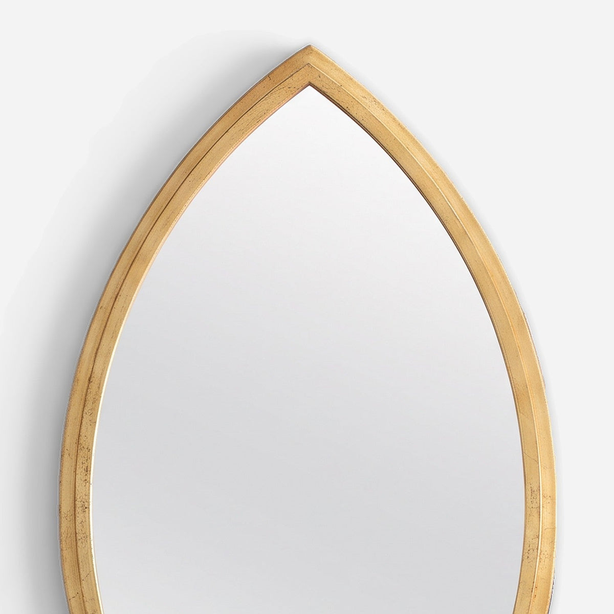 Pointed tip of a slim gold iron mirror frame with its fine inner step line, close-up detail