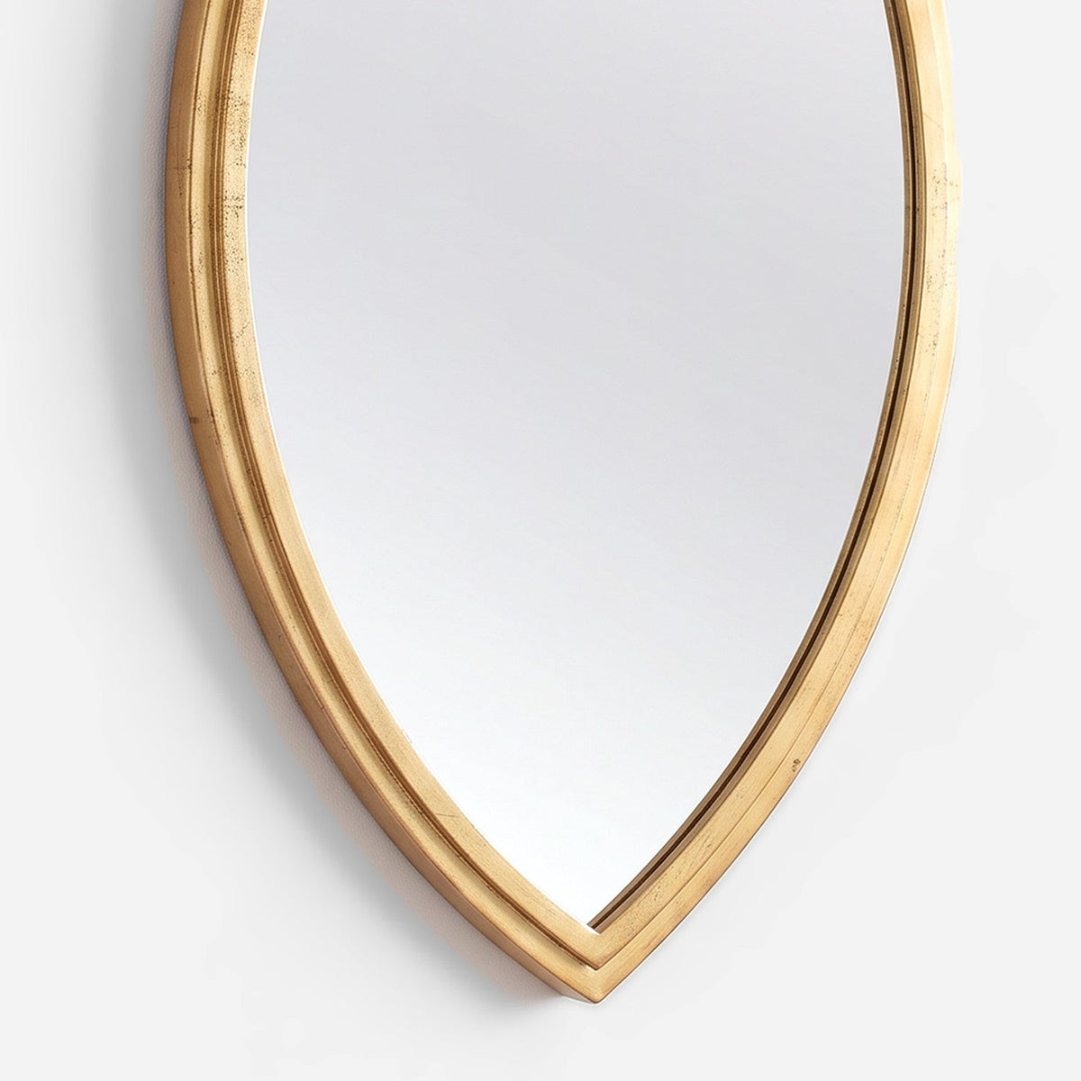 Stepped rim profile and soft gold lustre at the lower tip of the mirror frame, close-up detail