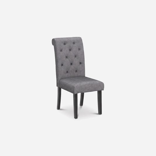 Turned view of a linen-look upholstered dining chair with button tufting and dark wood legs