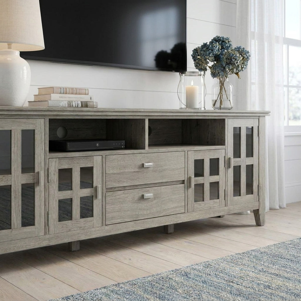 Closer view of the grey TV stand's glass doors and drawers, left end cut at the frame edge (close-up detail)