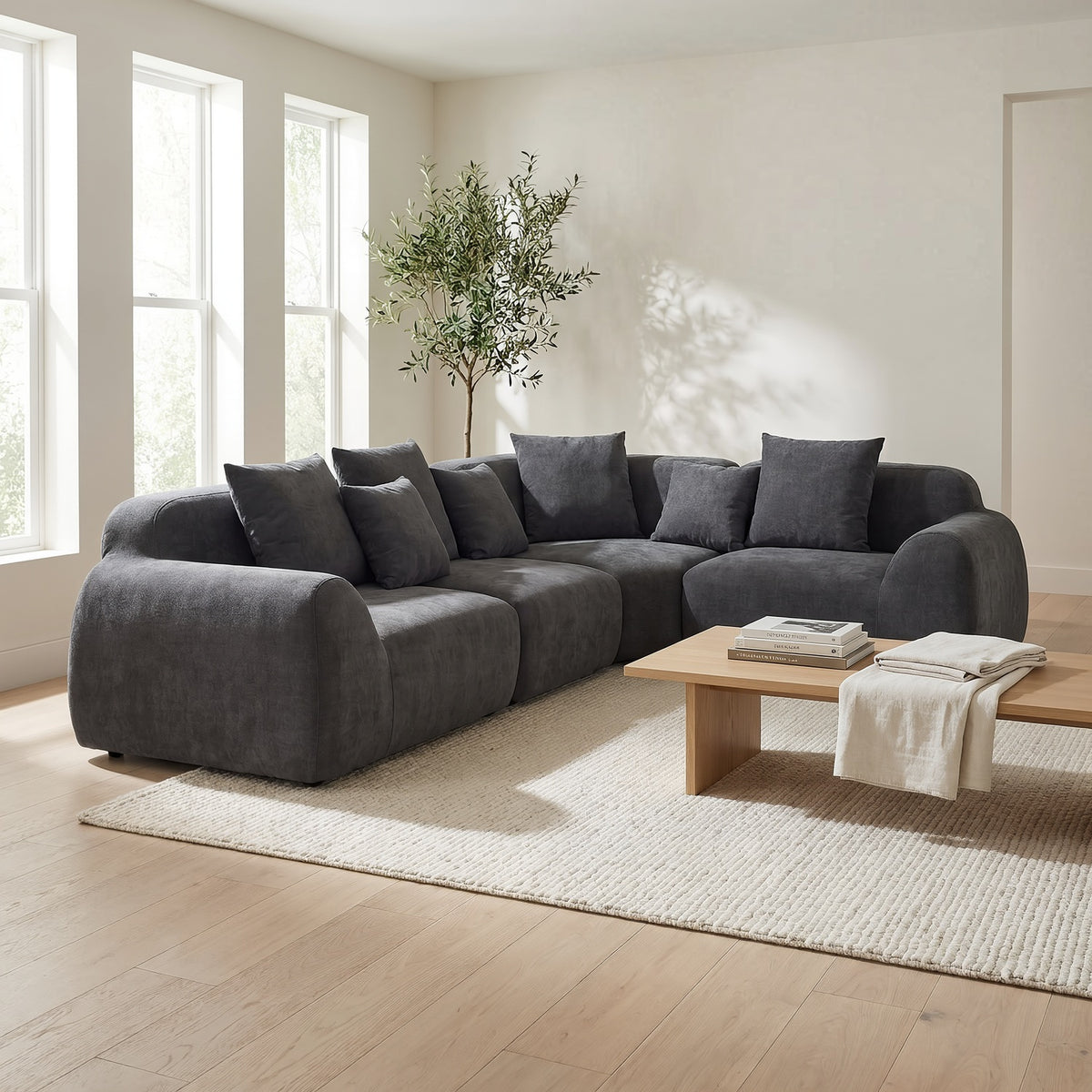 Grey velvet cloud sectional sofa with L-shaped chaise in a sunlit family living room, wide view (room scene)