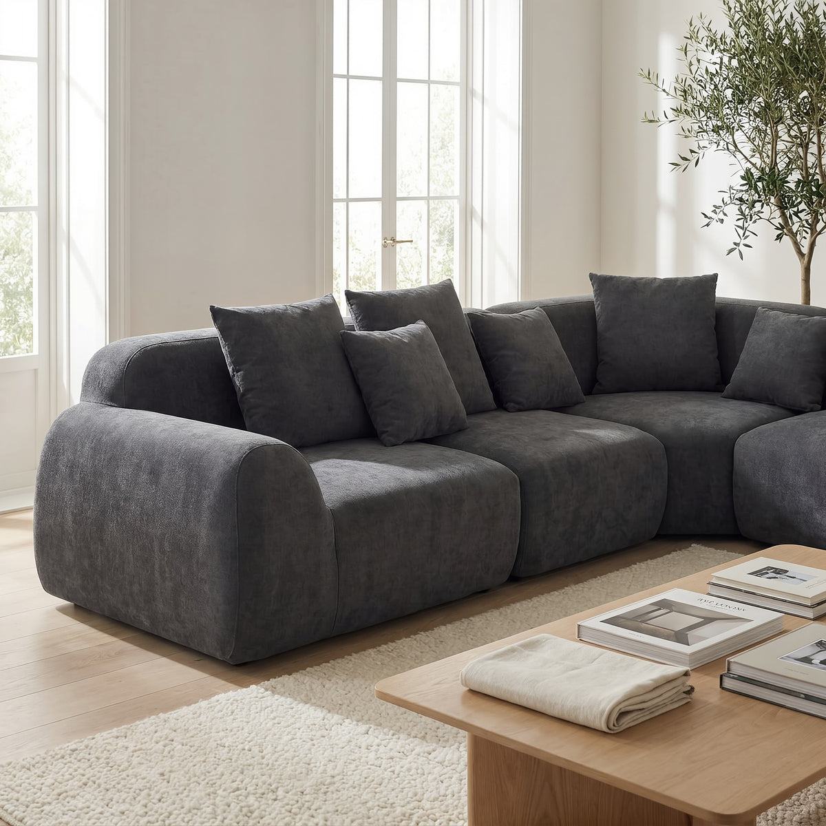 Grey velvet cloud sectional sofa in a sunlit living room beside an oak coffee table, closer view (room scene)