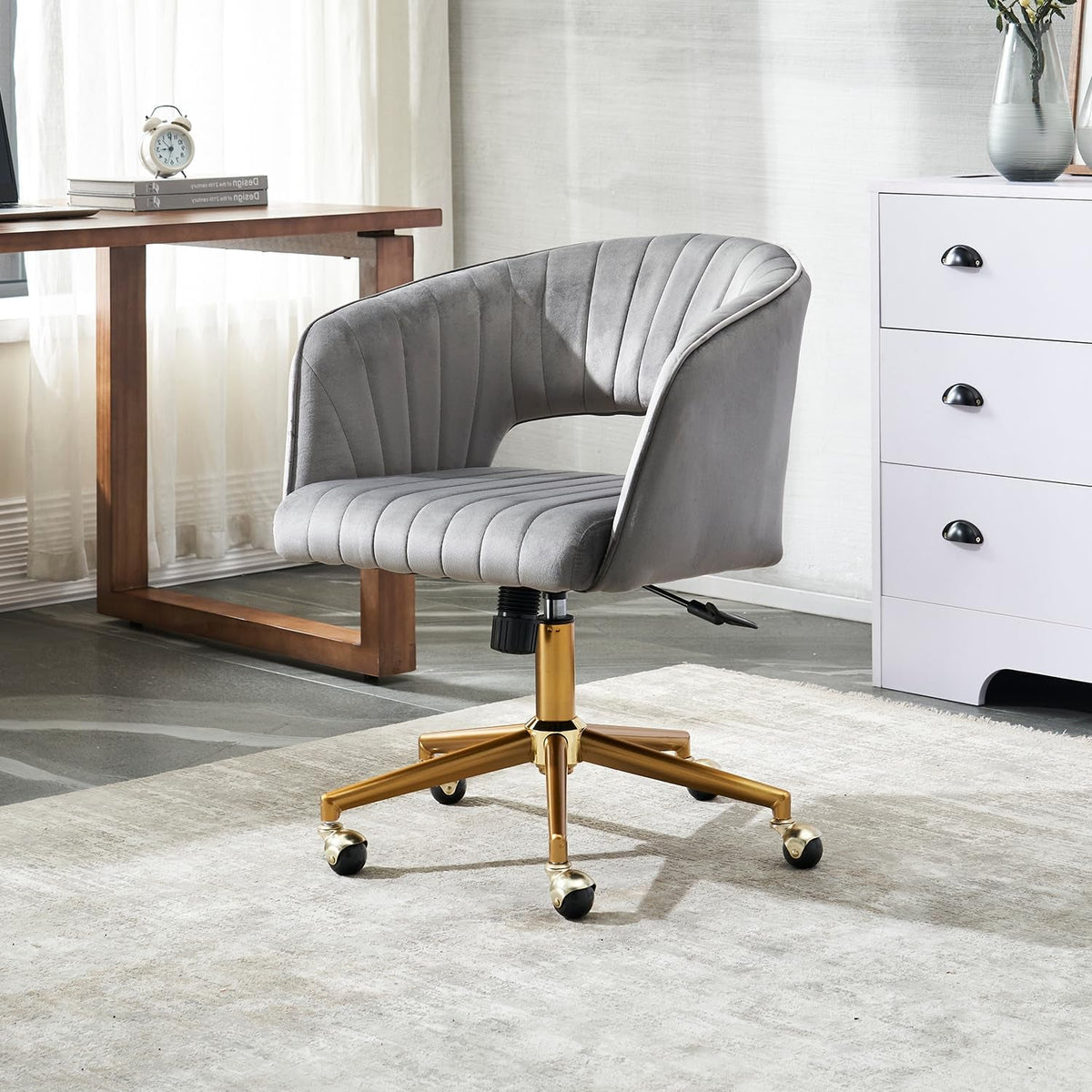 Velvet swivel chair on a pale rug beside a walnut desk and white drawer chest in a bright home office