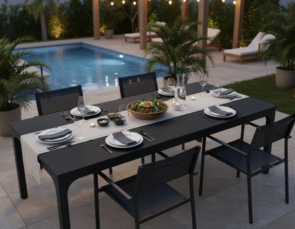 78-inch black 8-seater dining table by the pool, set with plates, glasses, candles, and a large salad bowl.