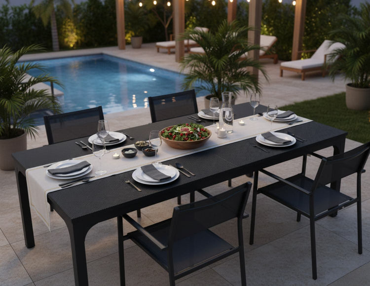 78-inch black 8-seater dining table by the pool, set with plates, glasses, candles, and a large salad bowl.