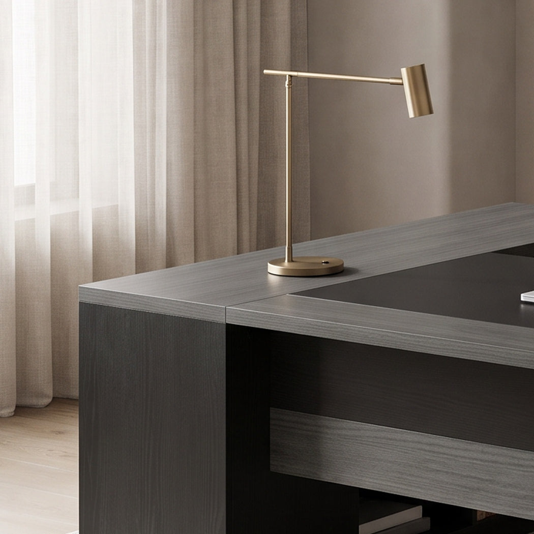 Close-up of the desk return corner with a brass lamp in a softly lit study