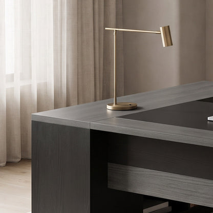 Close-up of the desk return corner with a brass lamp in a softly lit study