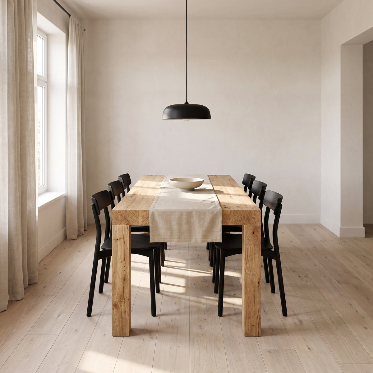 Light oak extendable dining table at full length under a black pendant in a white plaster dining room
