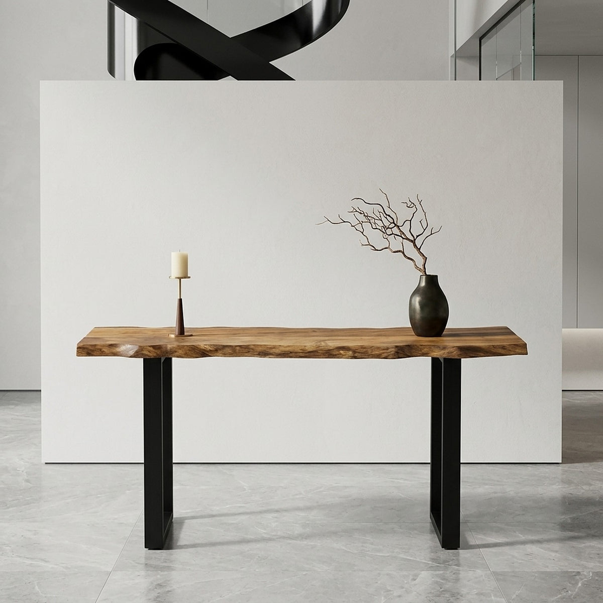 Front view of the acacia table against a white partition, styled with a candle and a branch in a dark vase