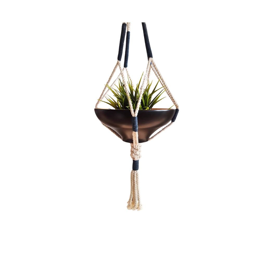 Handcrafted macrame plant hanger with navy wraps suspending a dark bowl planter, front view (plain studio)