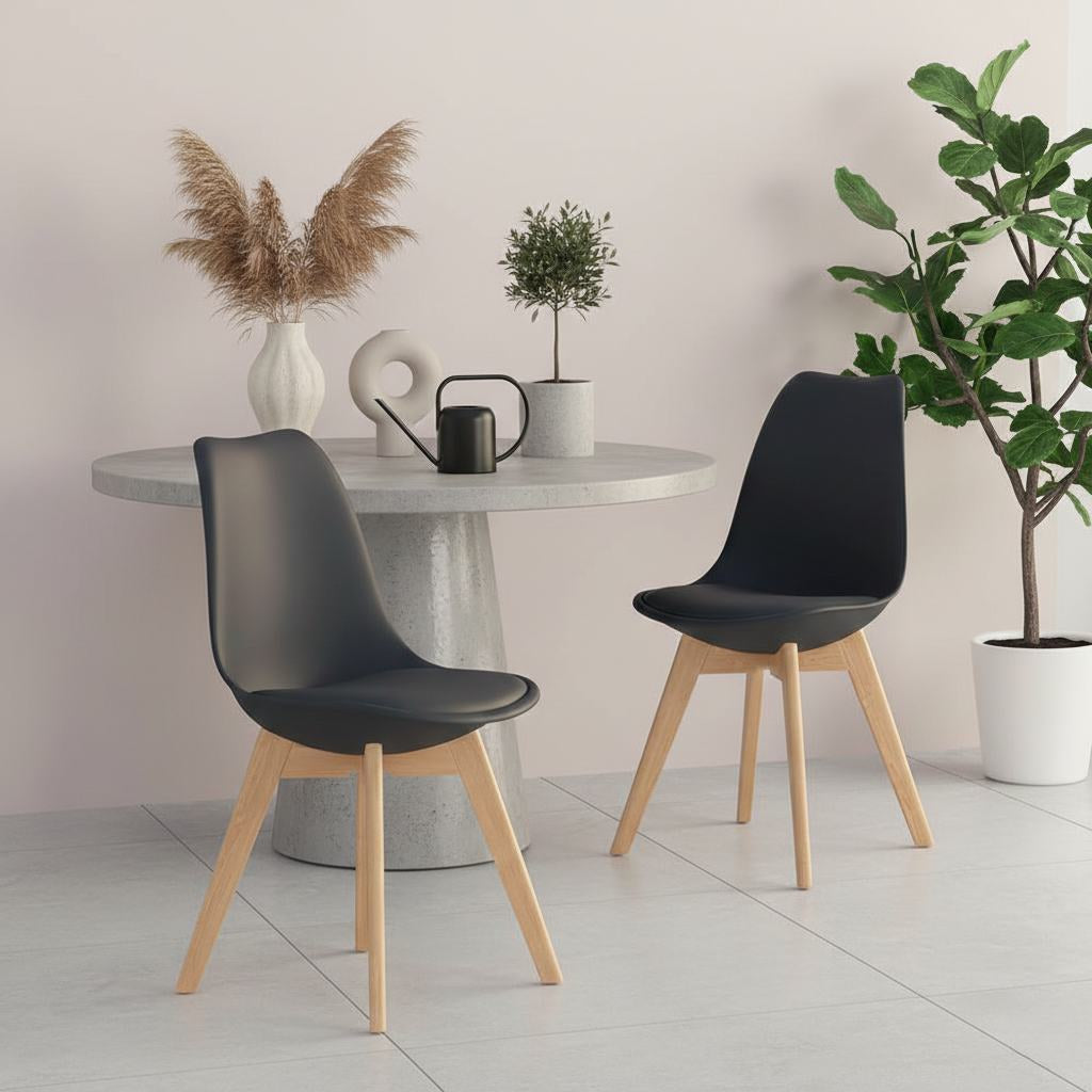 Mid-century modern black plastic-shell dining chairs with wooden legs, four-piece set around a round table.