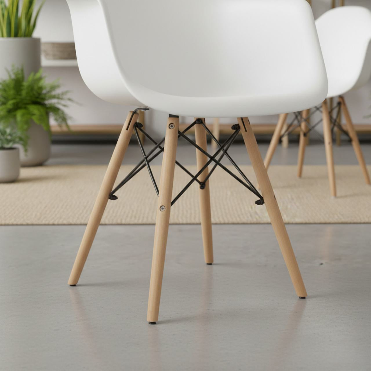 Set of 2 mid-century modern white molded dining armchairs with light wood legs and black metal cross supports.