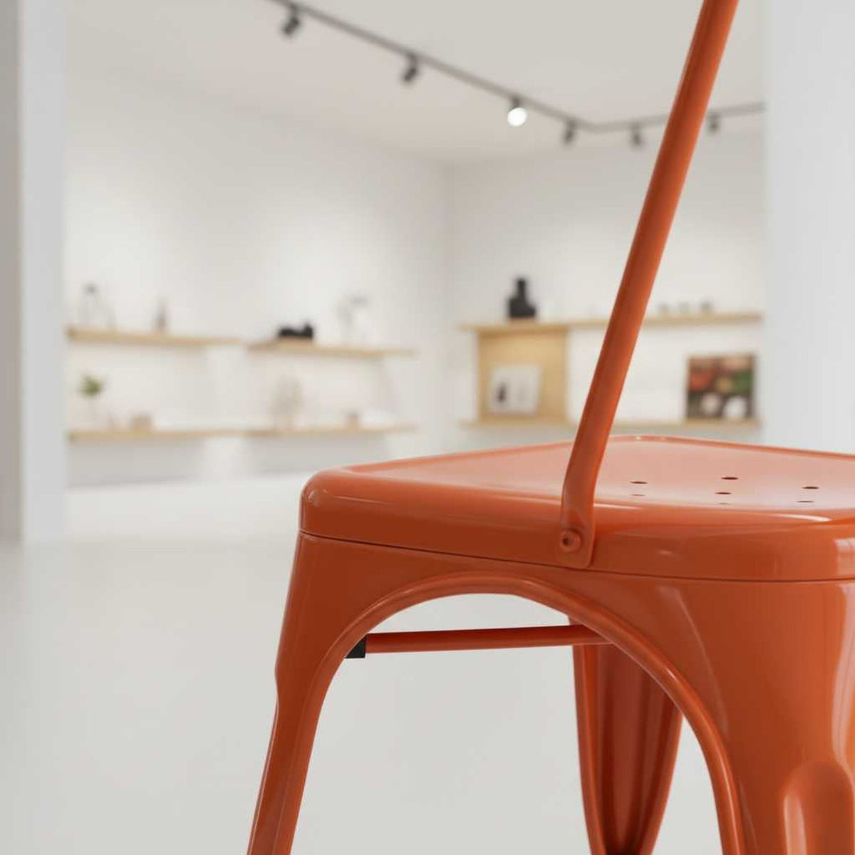 Vibrant rust metal dining chair with stackable design in a bright showroom (close-up detail)