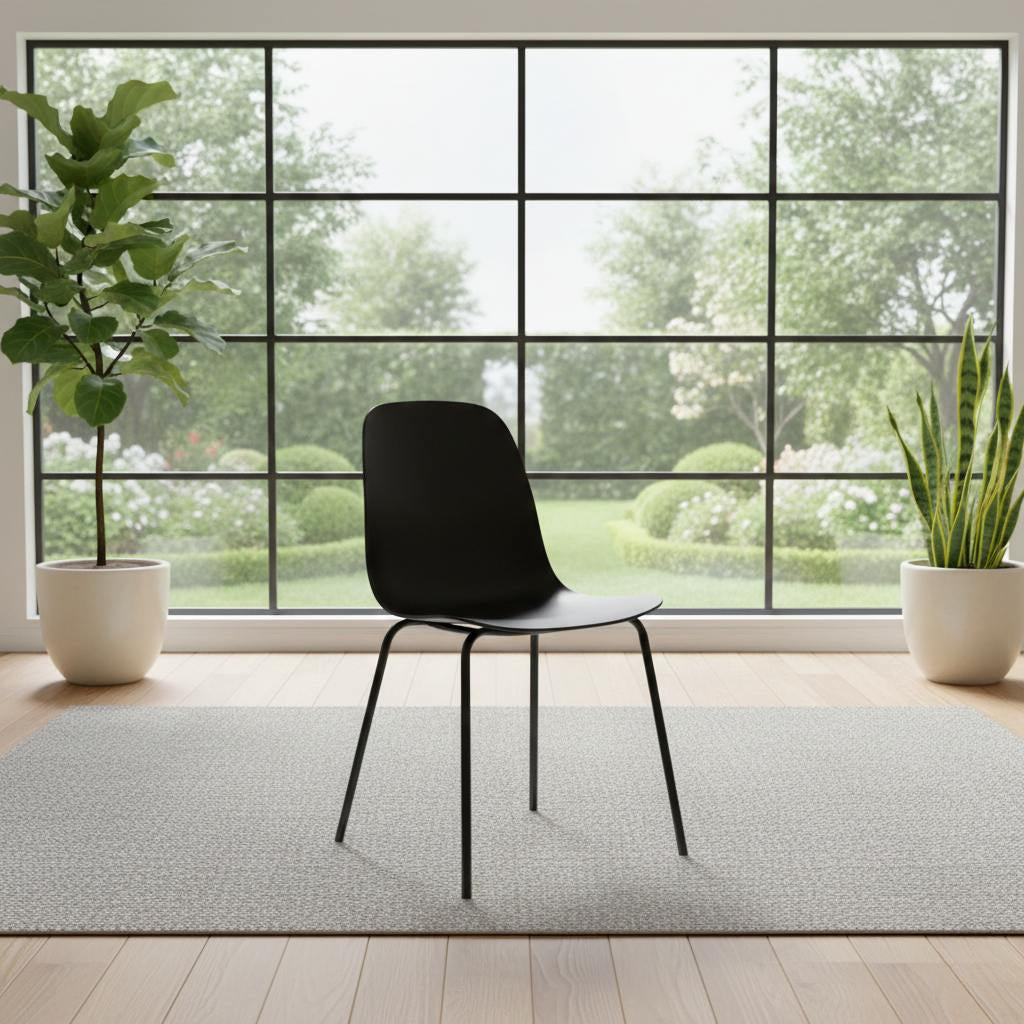 Set of four matte-black dining chairs with slender legs in a bright room, grid-window backdrop and potted plants